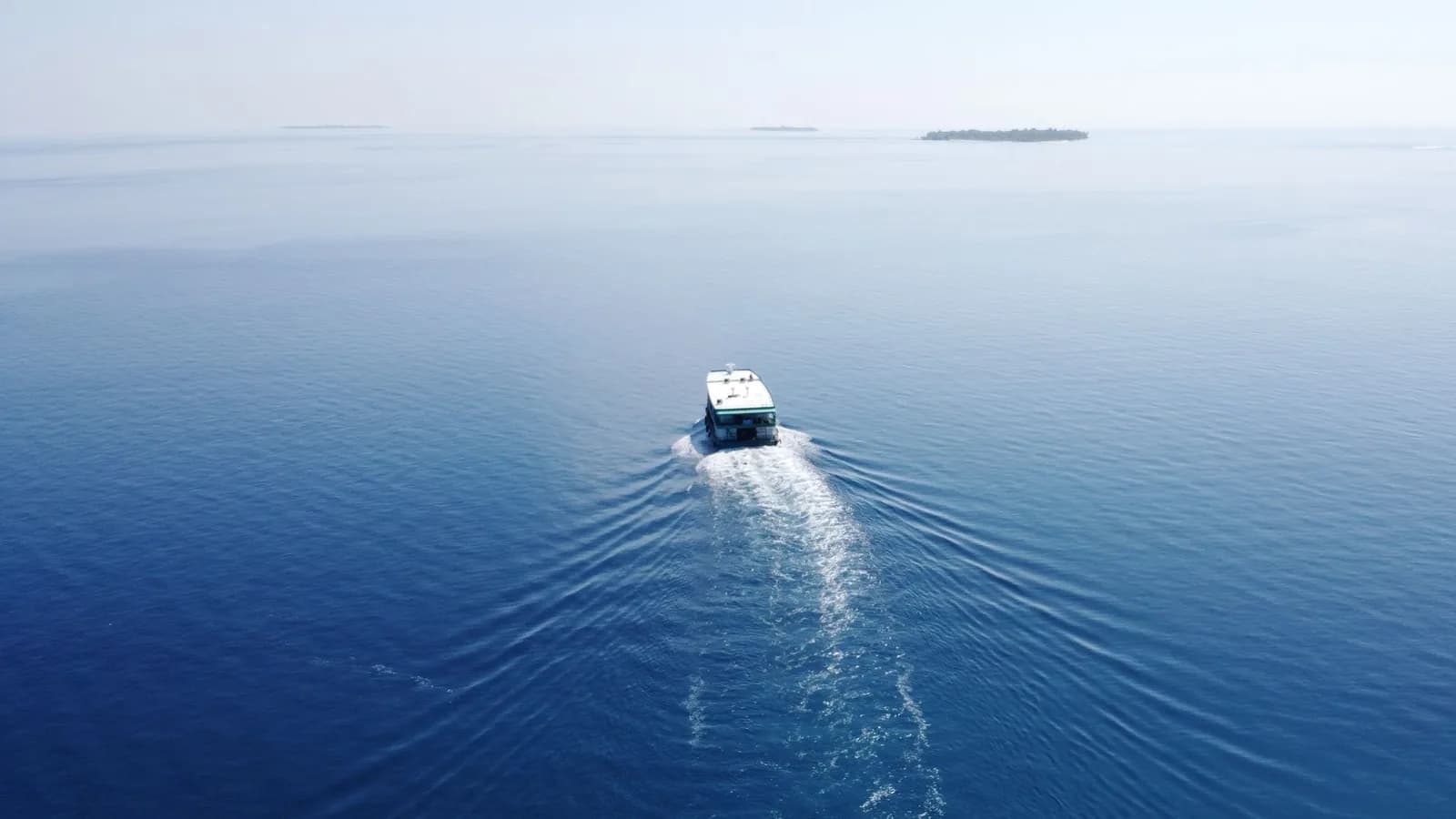 Fast boat traçant son sillage sur une mer plate en direction d'îles à l'horizon, comme sur la liaison Bali vers les Gili