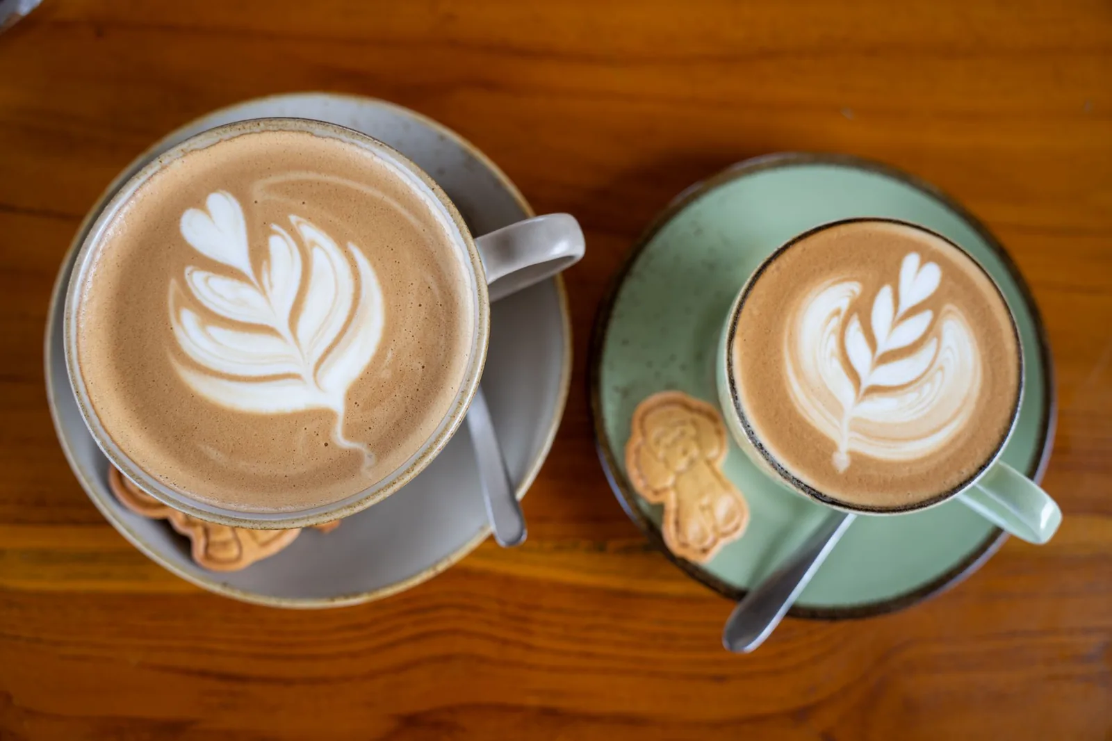 Deux cappuccinos au latte art posés sur une table en bois dans un café de Bali
