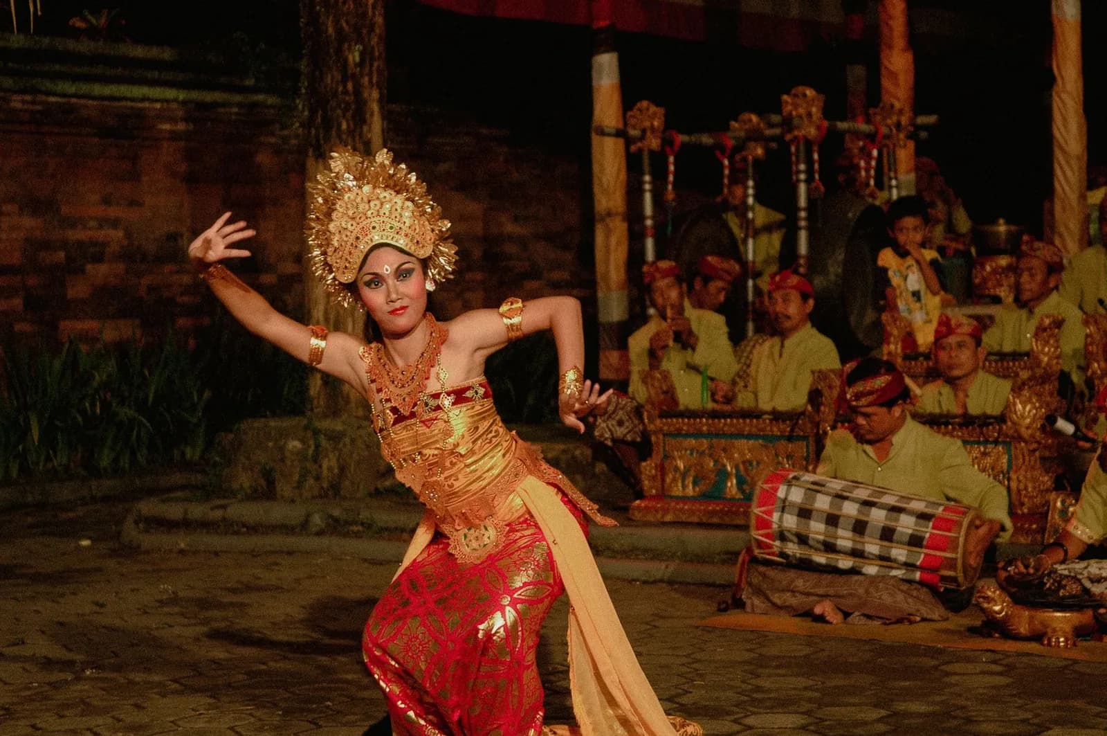 Danseuse balinaise en costume doré et couronne devant l'orchestre de gamelan lors d'un spectacle