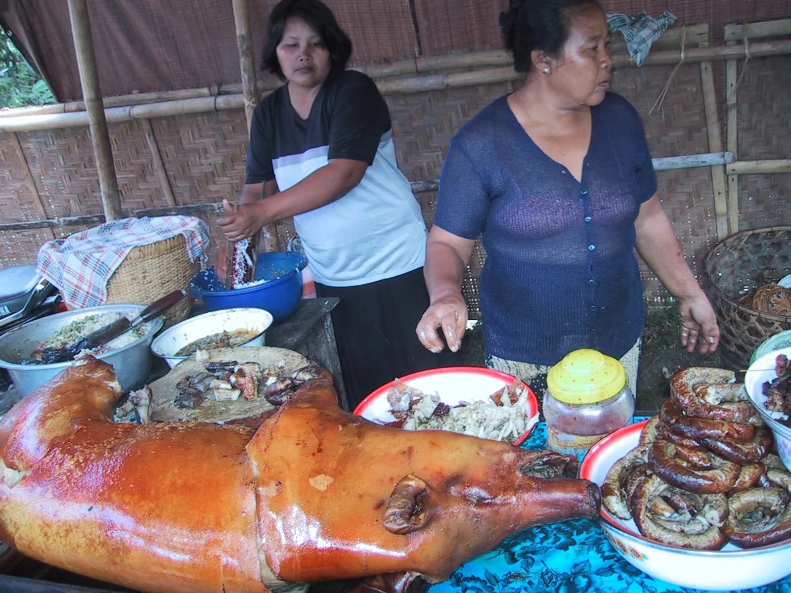 Deux femmes tiennent un étal de babi guling avec un cochon de lait rôti entier, à Bali