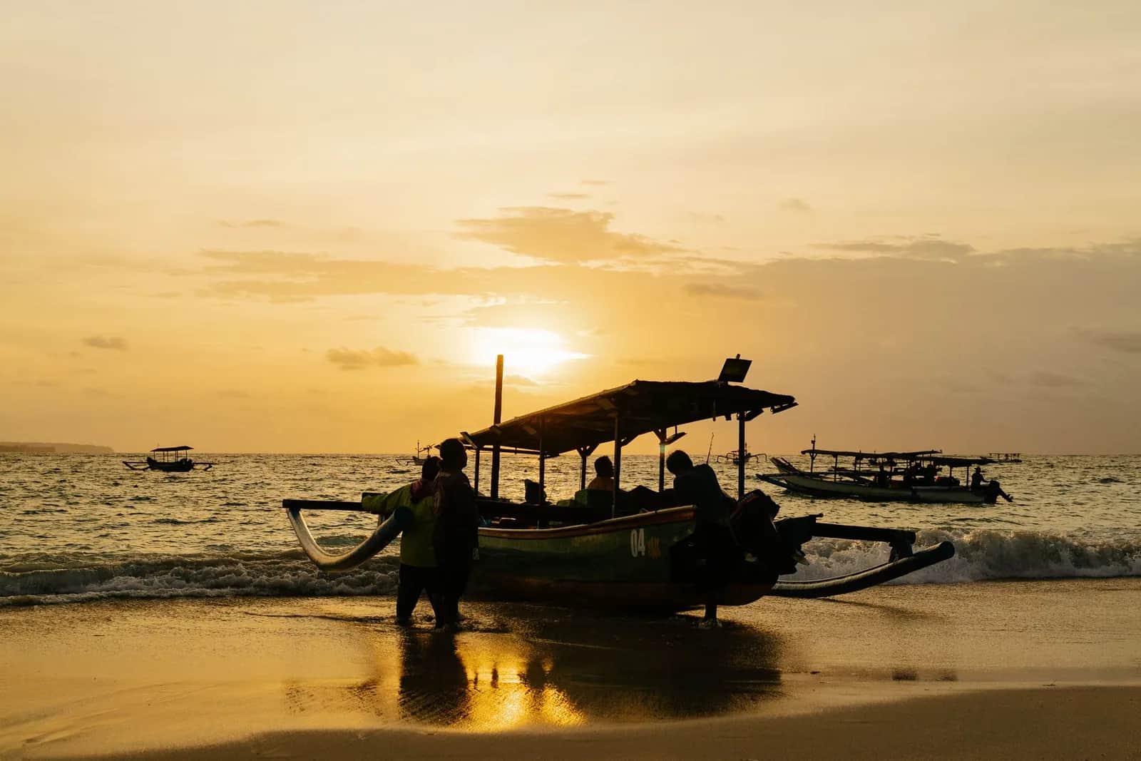 Jukung, bateau de pêche balinais, tiré sur le sable au coucher du soleil sur une plage de la côte ouest de Bali