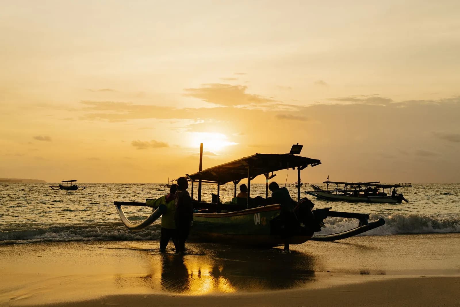 Jukung, bateau de pêche balinais, tiré sur le sable au coucher du soleil sur une plage de la côte ouest de Bali