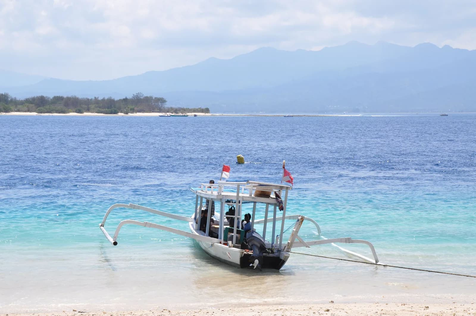 Bateau à balancier battant pavillon de plongée, échoué sur le sable devant Gili Trawangan, avec Lombok en face