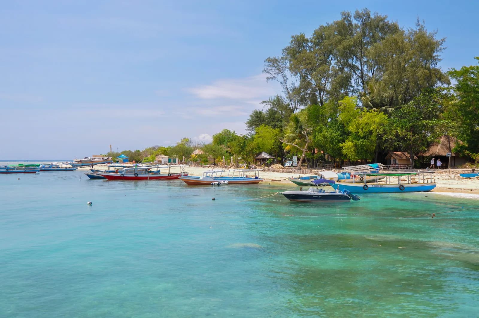 Flotte de bateaux en bois au mouillage devant le débarcadère des îles Gili, dans une eau turquoise peu profonde