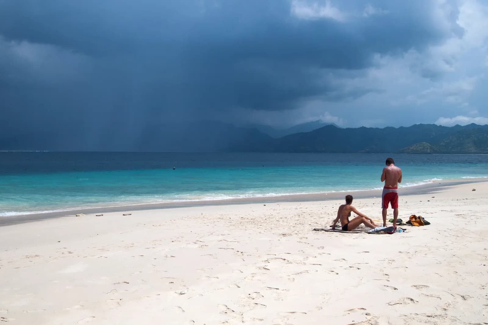 Plage de sable blanc quasi déserte de Gili Meno, avec Lombok et un grain tropical à l'horizon