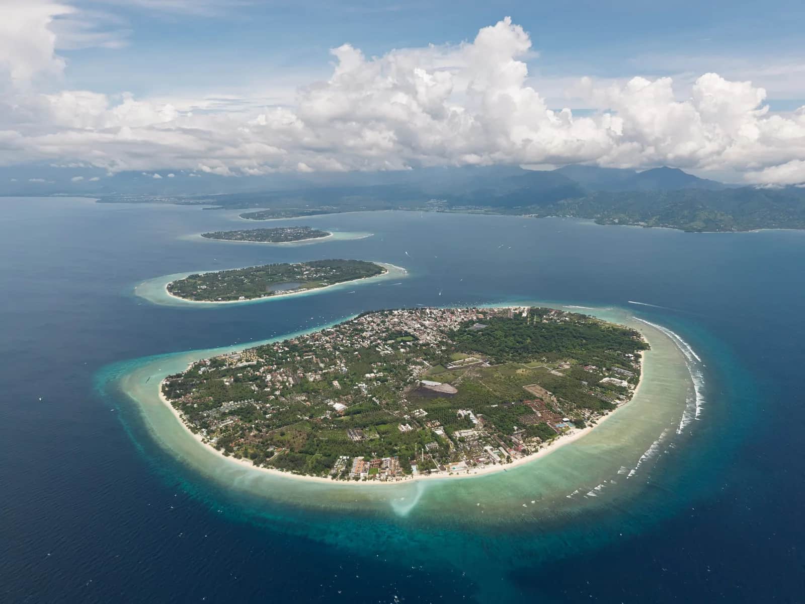 Vue aérienne des trois îles Gili alignées au large de Lombok : Gili Trawangan au premier plan, Gili Meno et Gili Air derrière