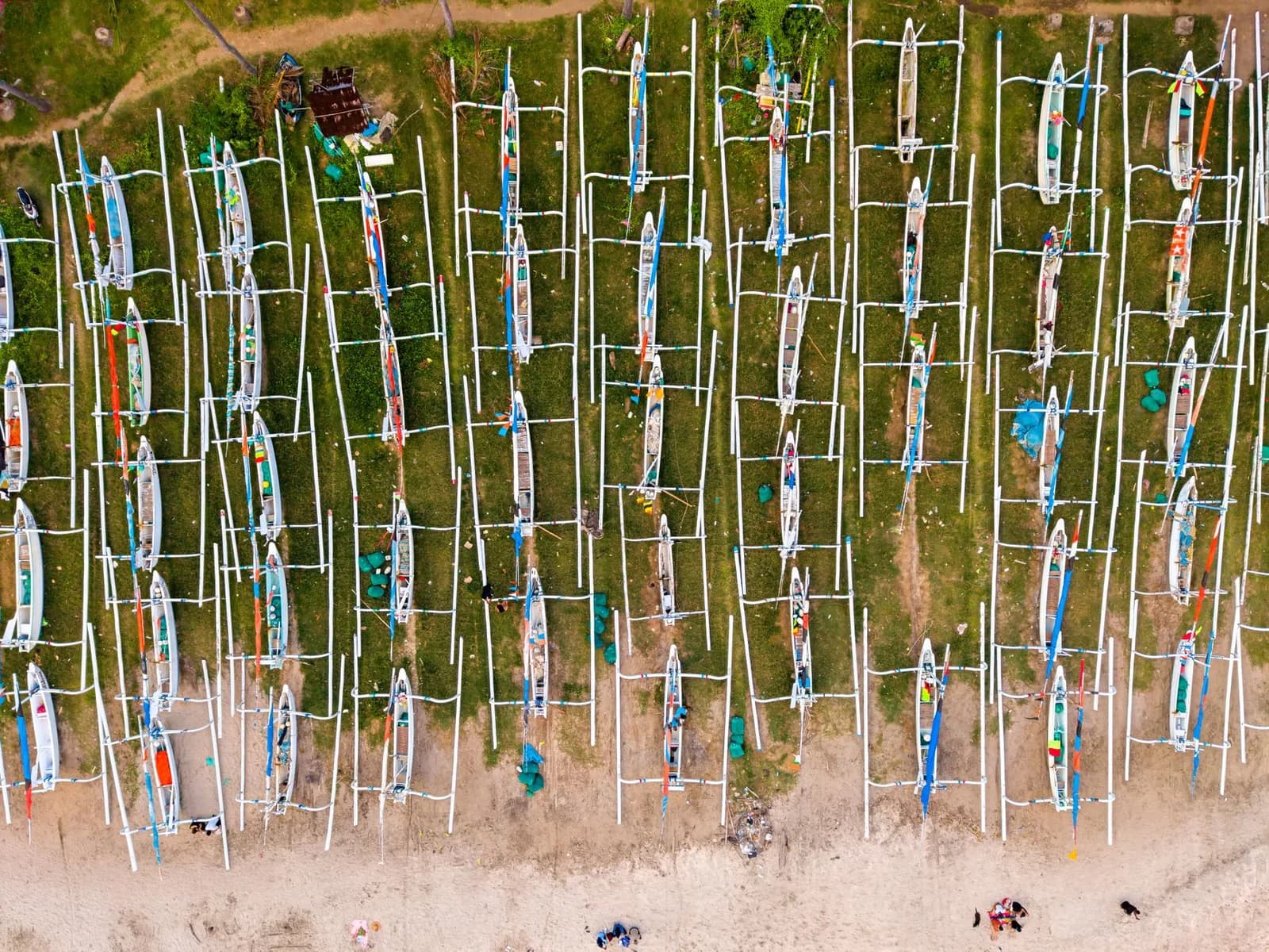 Vue aérienne de dizaines de bateaux de pêche jukung à balancier alignés sur le rivage d'un village de pêcheurs balinais