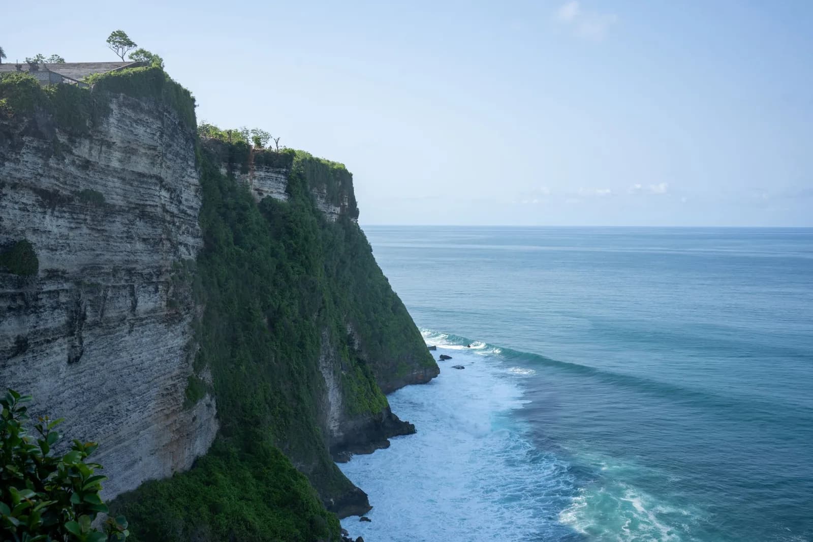 Falaises calcaires d'Uluwatu plongeant dans l'océan Indien au sud de Bali, bâtiments du temple visibles sur le plateau