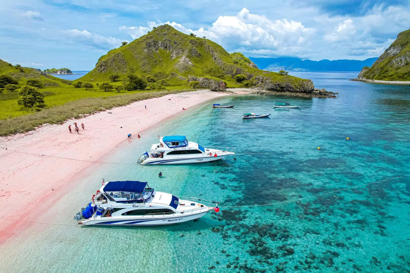 Speedboats d'excursion au mouillage dans une baie turquoise près de Pink Beach, parc national de Komodo