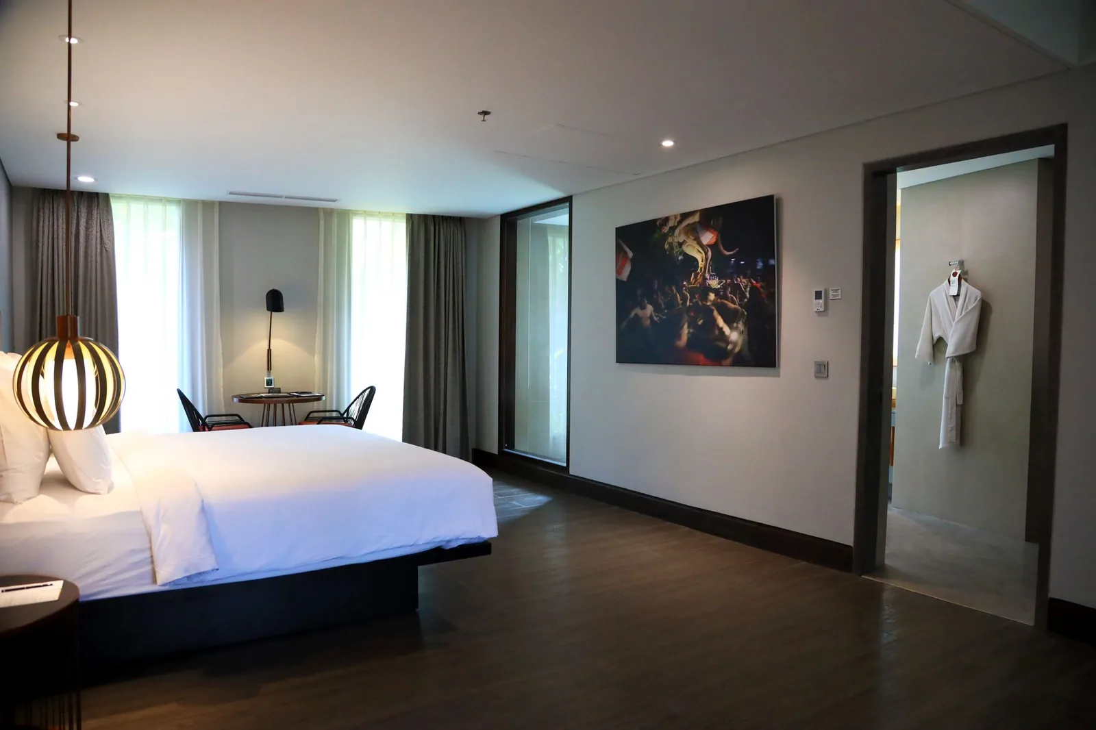 Chambre d'hôtel moderne à Bali, lit king size, parquet foncé et baie vitrée sur la végétation, comme dans les hôtels de Kuta et Legian