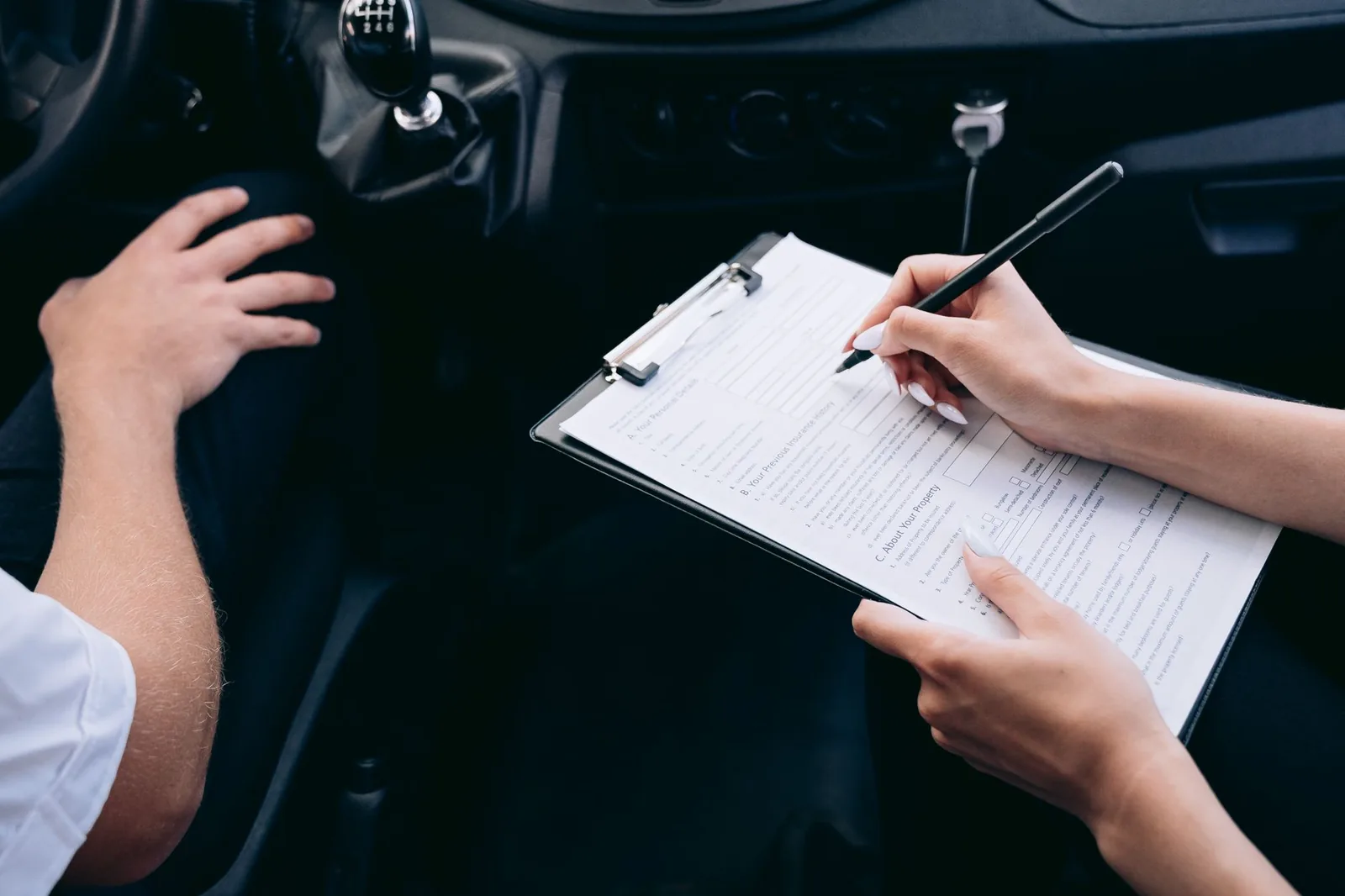Signature d'un contrat de location de voiture sur une planchette, à l'intérieur du véhicule