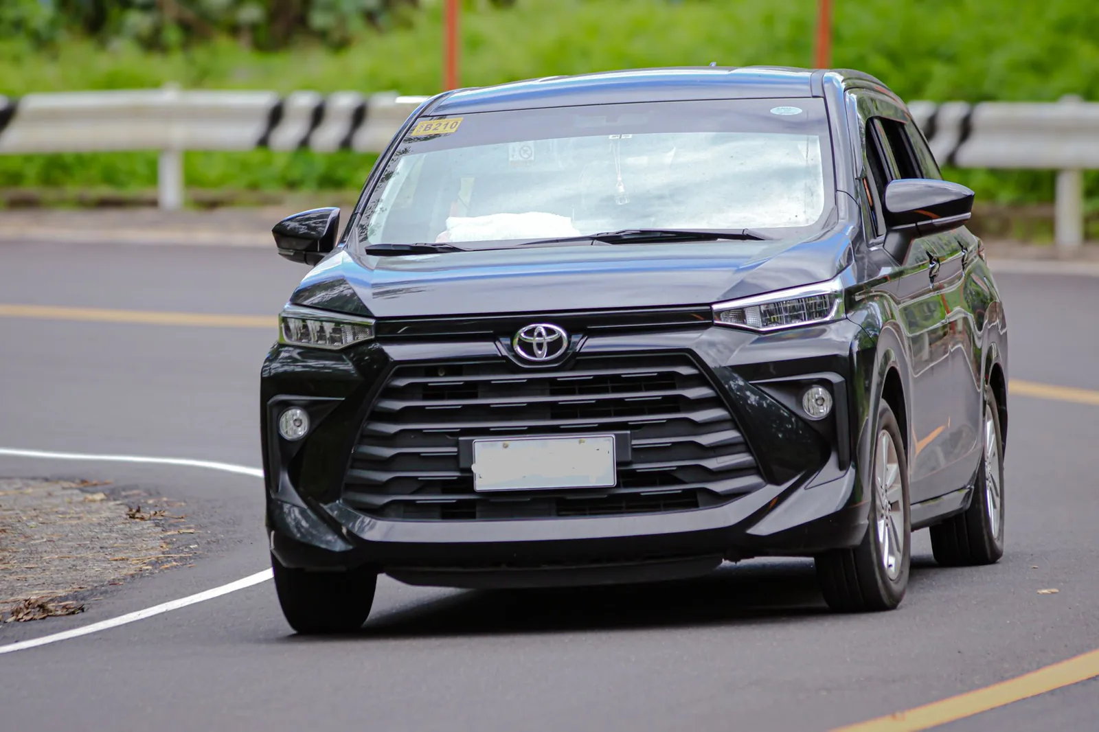 Toyota Avanza noire sur une route indonésienne, le monospace le plus courant des locations avec chauffeur à Bali
