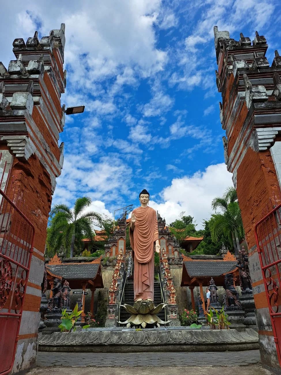 Statue de Bouddha debout encadrée par les portes d'un monastère bouddhiste balinais