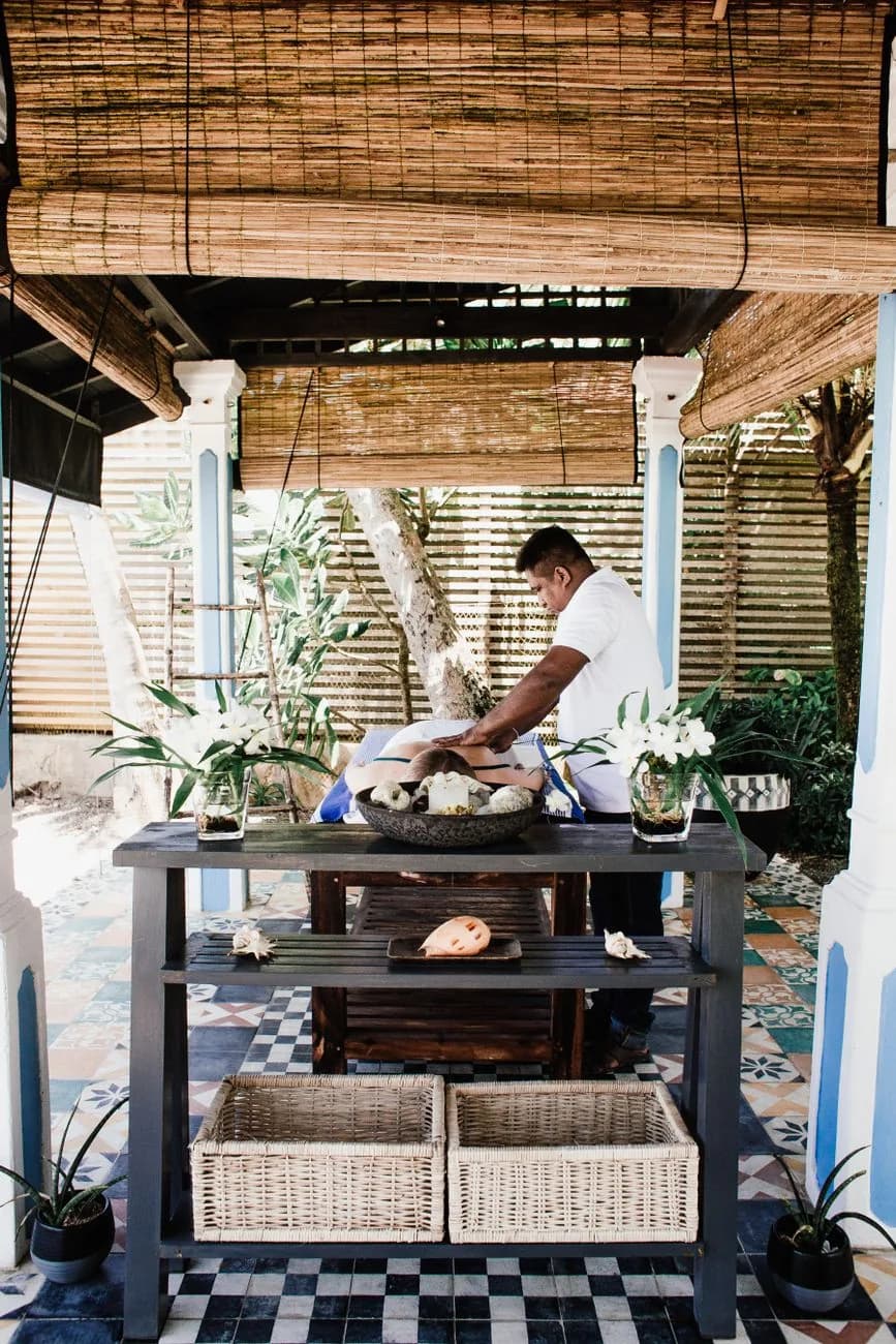 Massage sur une table installée sous un pavillon à stores de bambou ouvert sur un jardin tropical, Bali