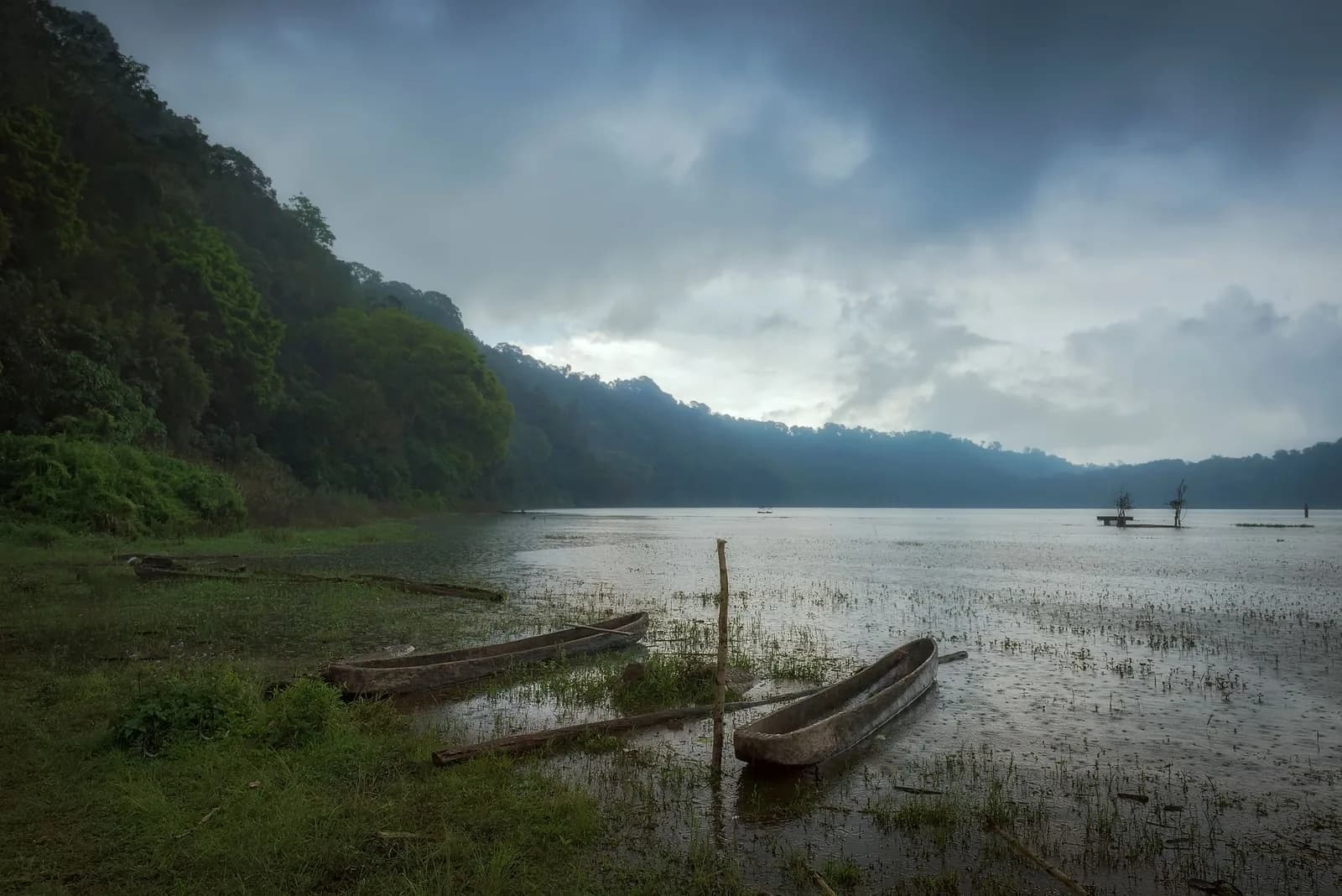 Pirogues en bois sur un lac de montagne sous un ciel chargé, Bali
