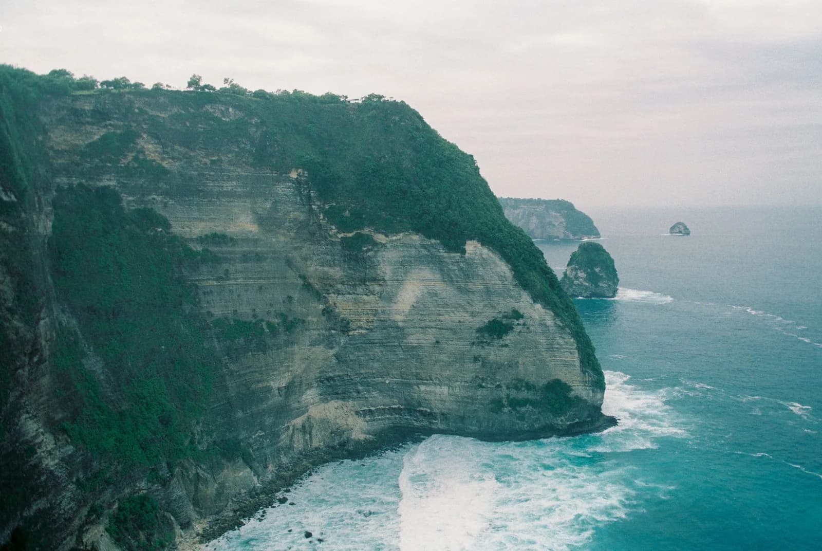 Falaises abruptes et boisées de la côte ouest de Nusa Penida tombant dans l'océan, Bali