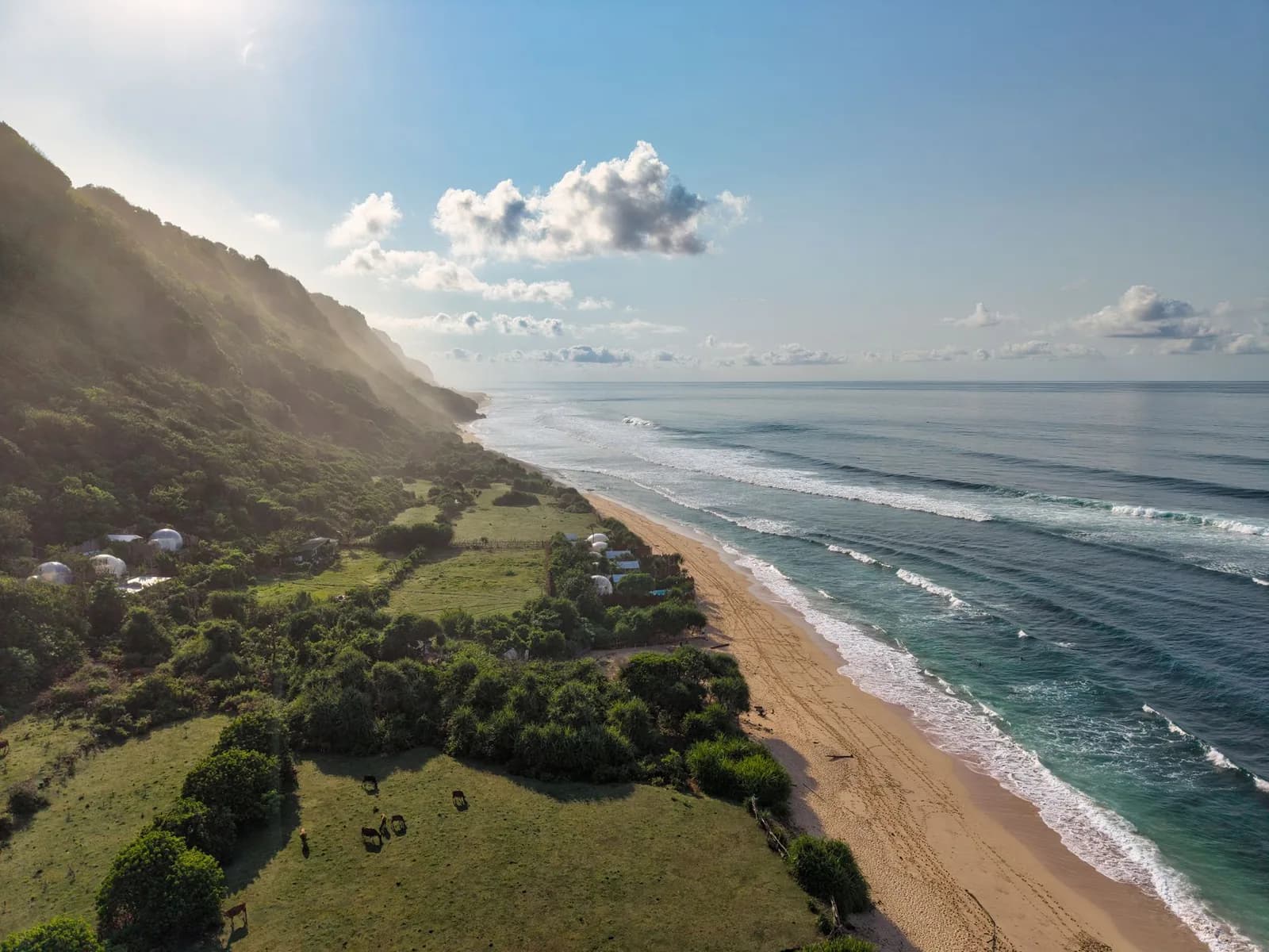 Longue plage de sable déserte de Nyang Nyang au pied d'une colline verte, au sud de Bali