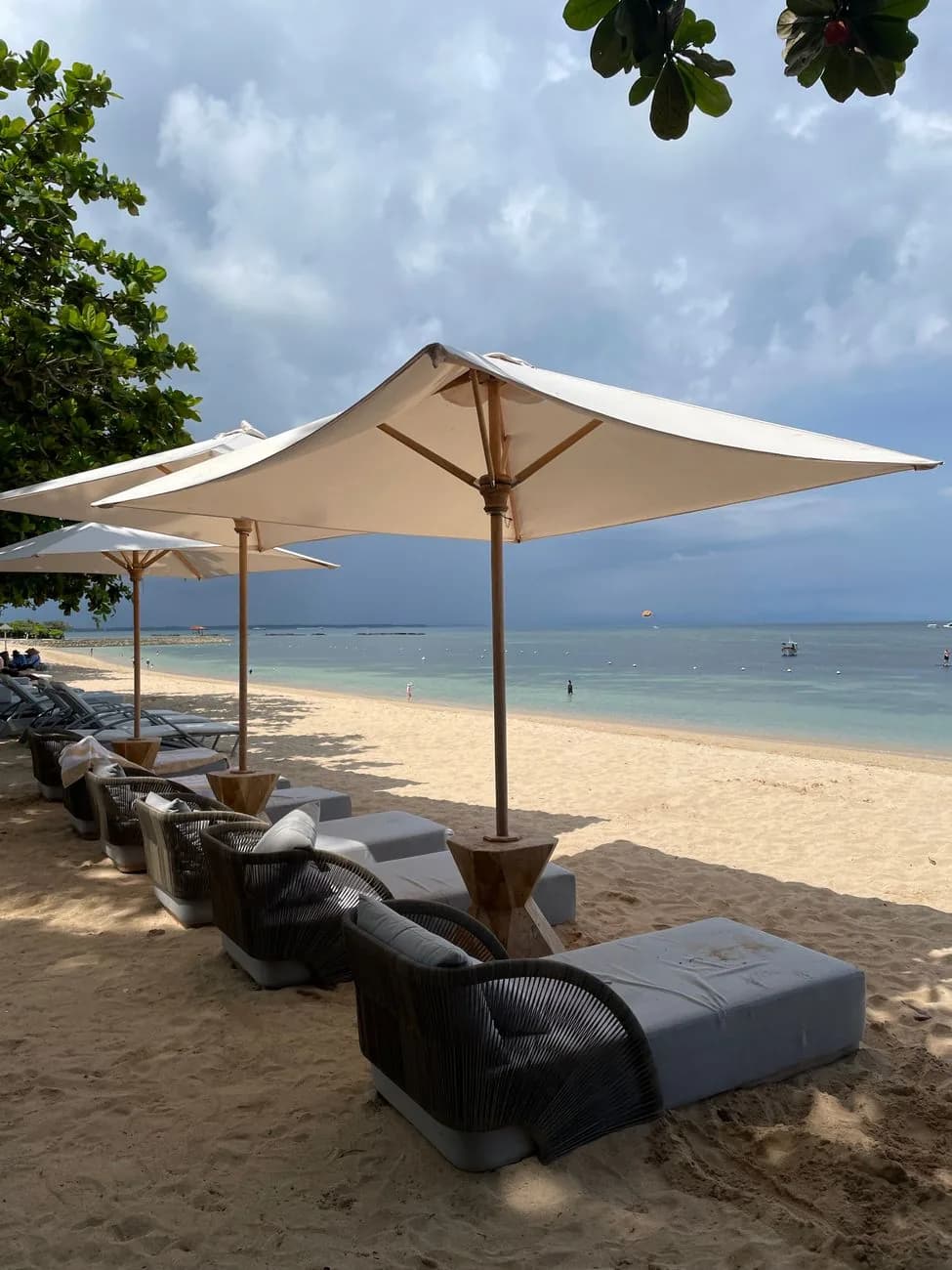 Transats et parasols sur le sable devant le lagon calme de Nusa Dua, station balnéaire du sud de Bali