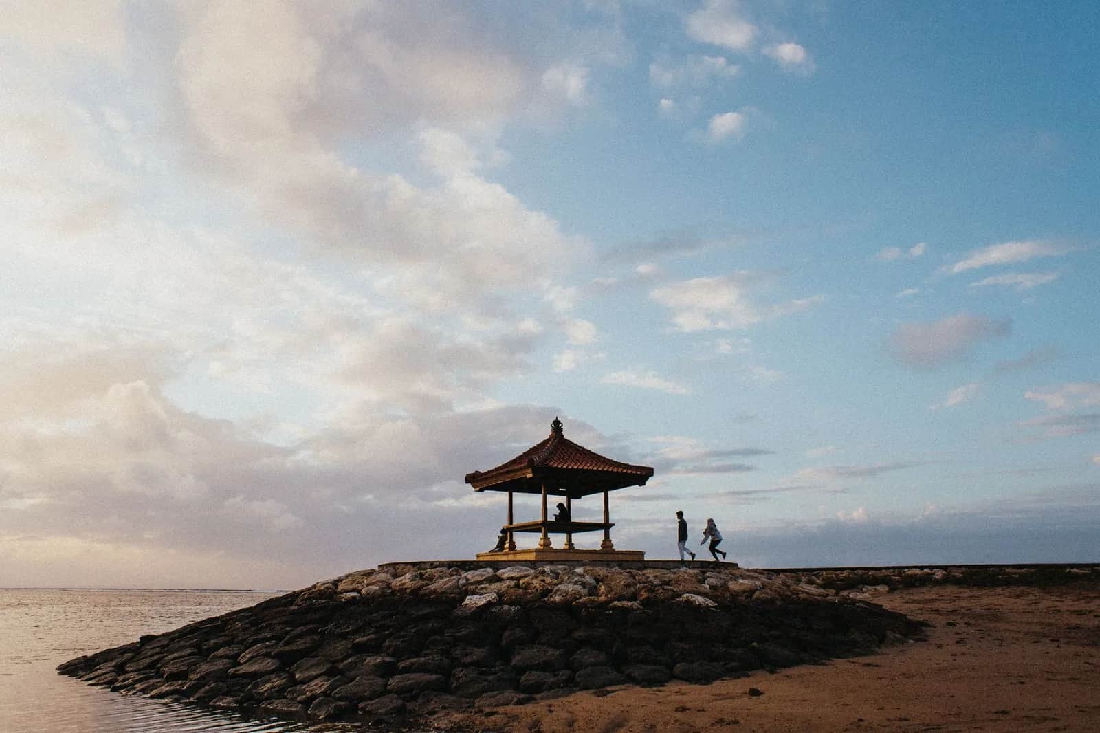Bale balinais à toit de tuiles posé sur le brise-lames de pierre de la plage de Sanur, à Bali, face à la mer calme