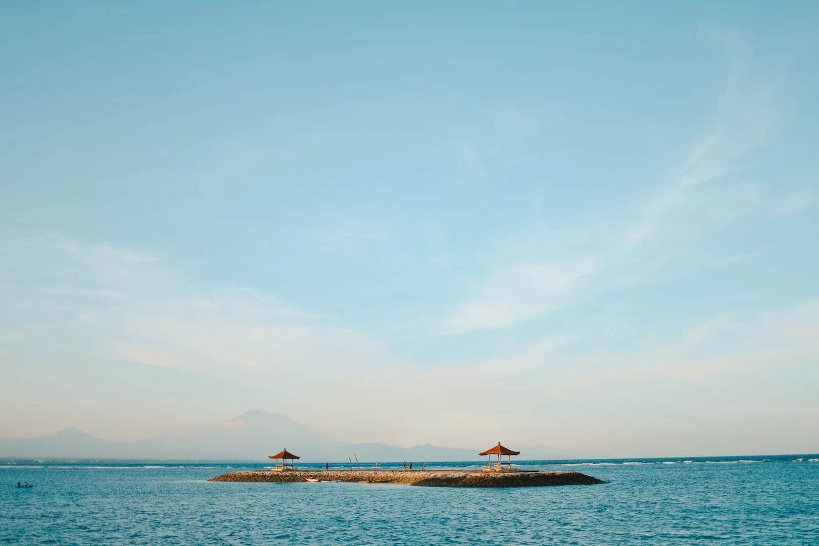 Deux bale balinais sur une jetée de pierre à Sanur, lagon turquoise et mont Agung à l'horizon