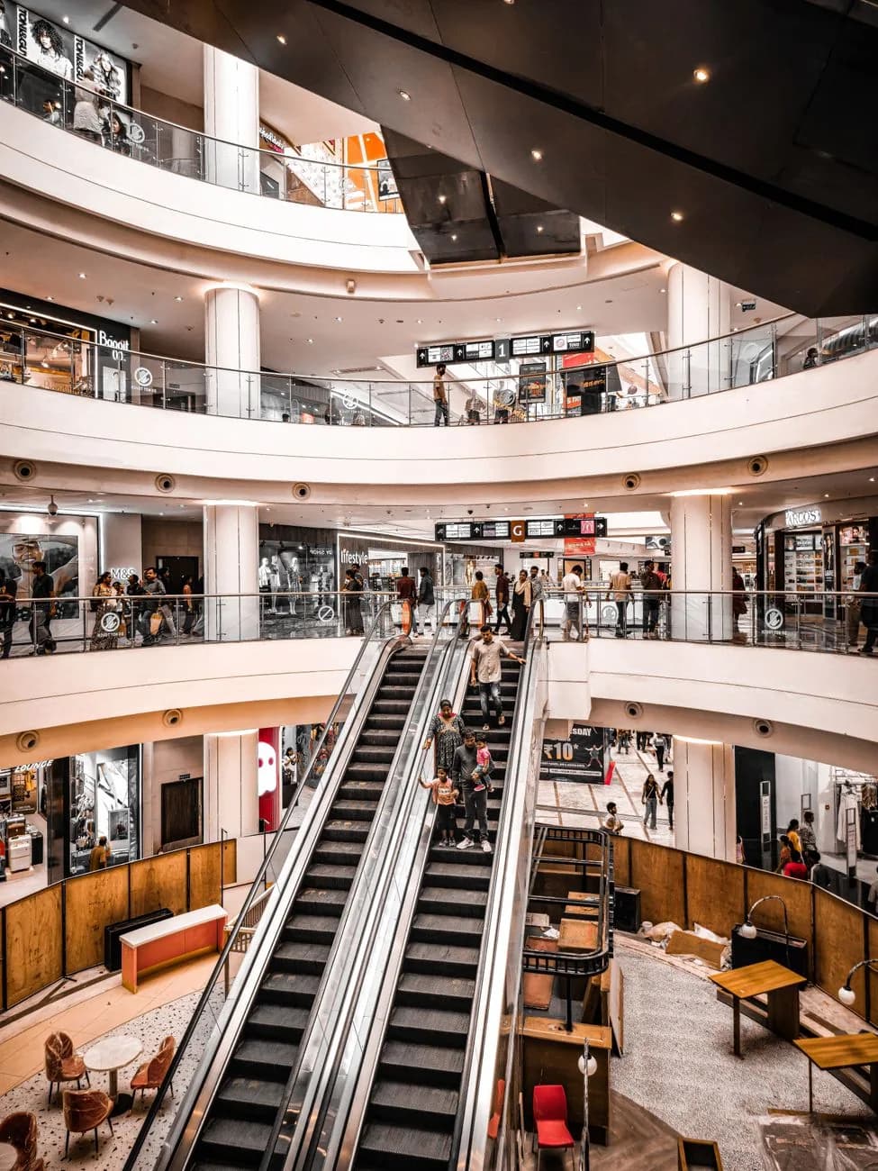 Intérieur d'un centre commercial moderne sur plusieurs niveaux avec escaliers mécaniques et boutiques, comme à Icon Bali Mall à Sanur