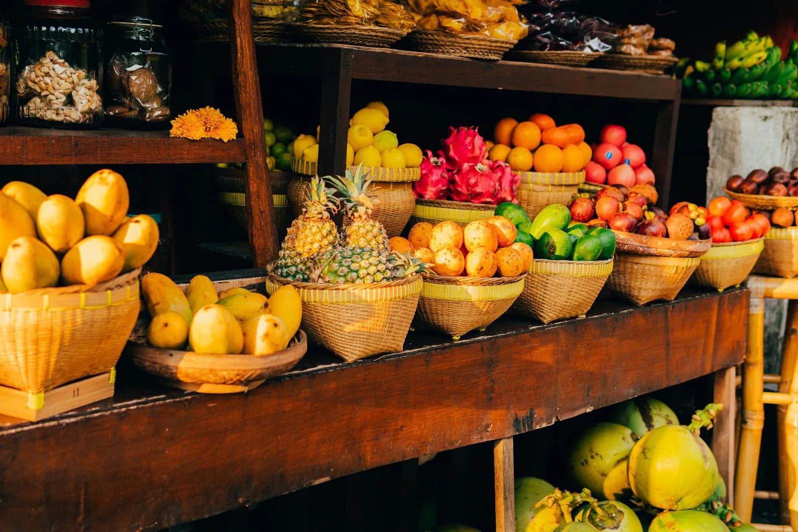 Étal de fruits tropicaux en paniers tressés, mangoustans, fruits du dragon, mangues et noix de coco, sur un marché de Bali