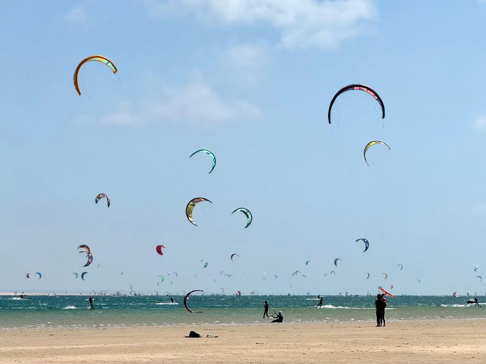 Dizaines de voiles de kitesurf au-dessus d'une eau plate et peu profonde, comme au spot de Mertasari au sud de Sanur en saison sèche