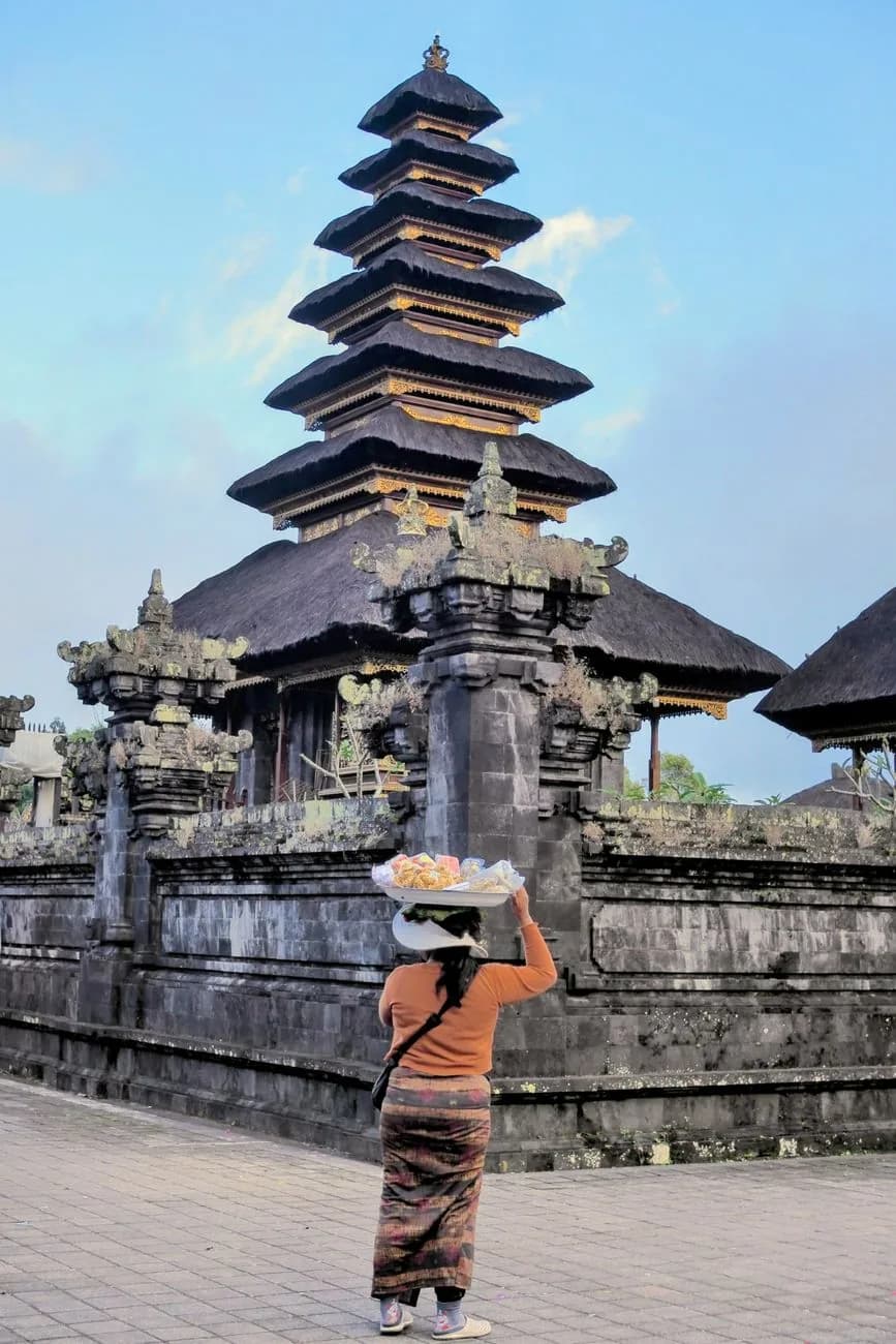 Femme balinaise portant une offrande devant un meru du temple de Besakih, Bali