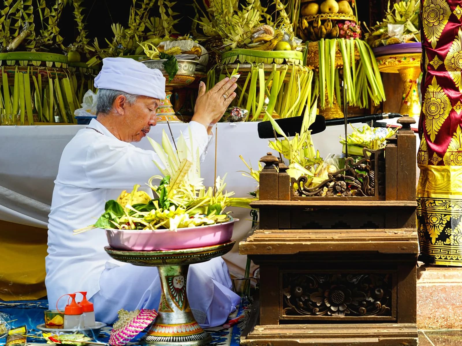 Prêtre balinais en blanc déposant des offrandes lors d'une cérémonie, comme lors des fêtes de temple de Pura Blanjong à Sanur
