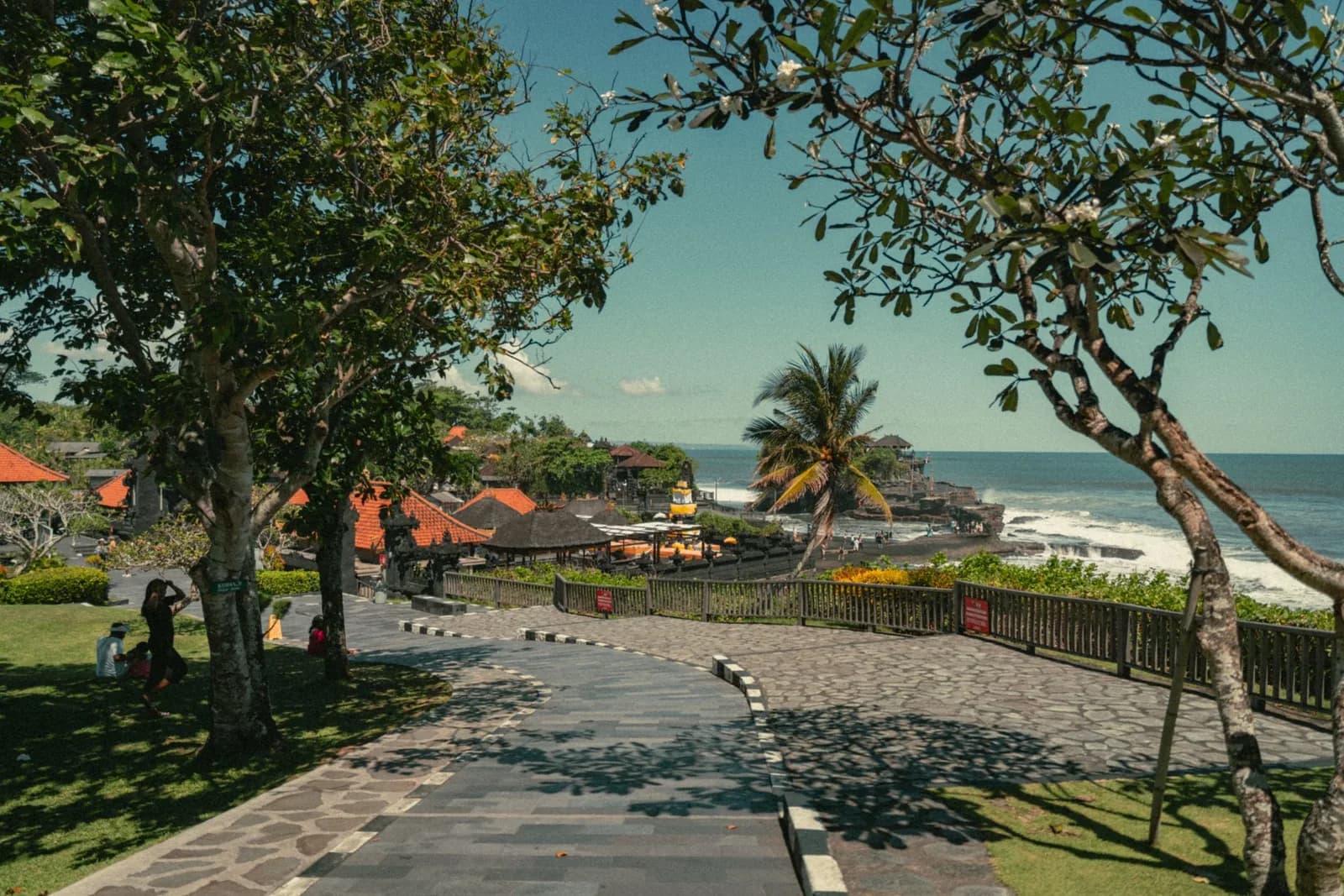 Esplanade et jardins du site de Tanah Lot avec le temple sur son rocher en arrière-plan, Bali