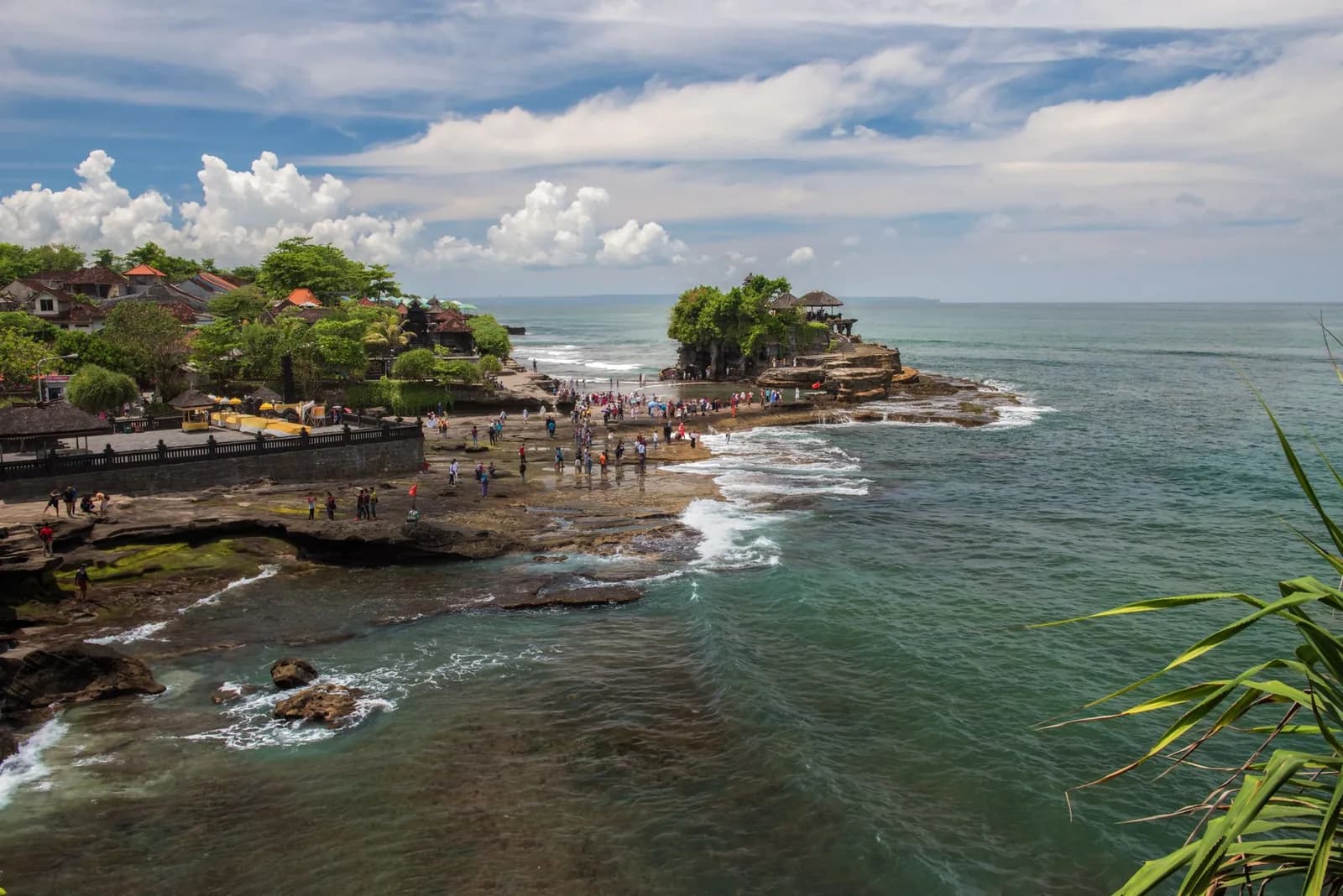 Visiteurs traversant le platier rocheux à pied vers le temple de Tanah Lot à marée basse, Bali