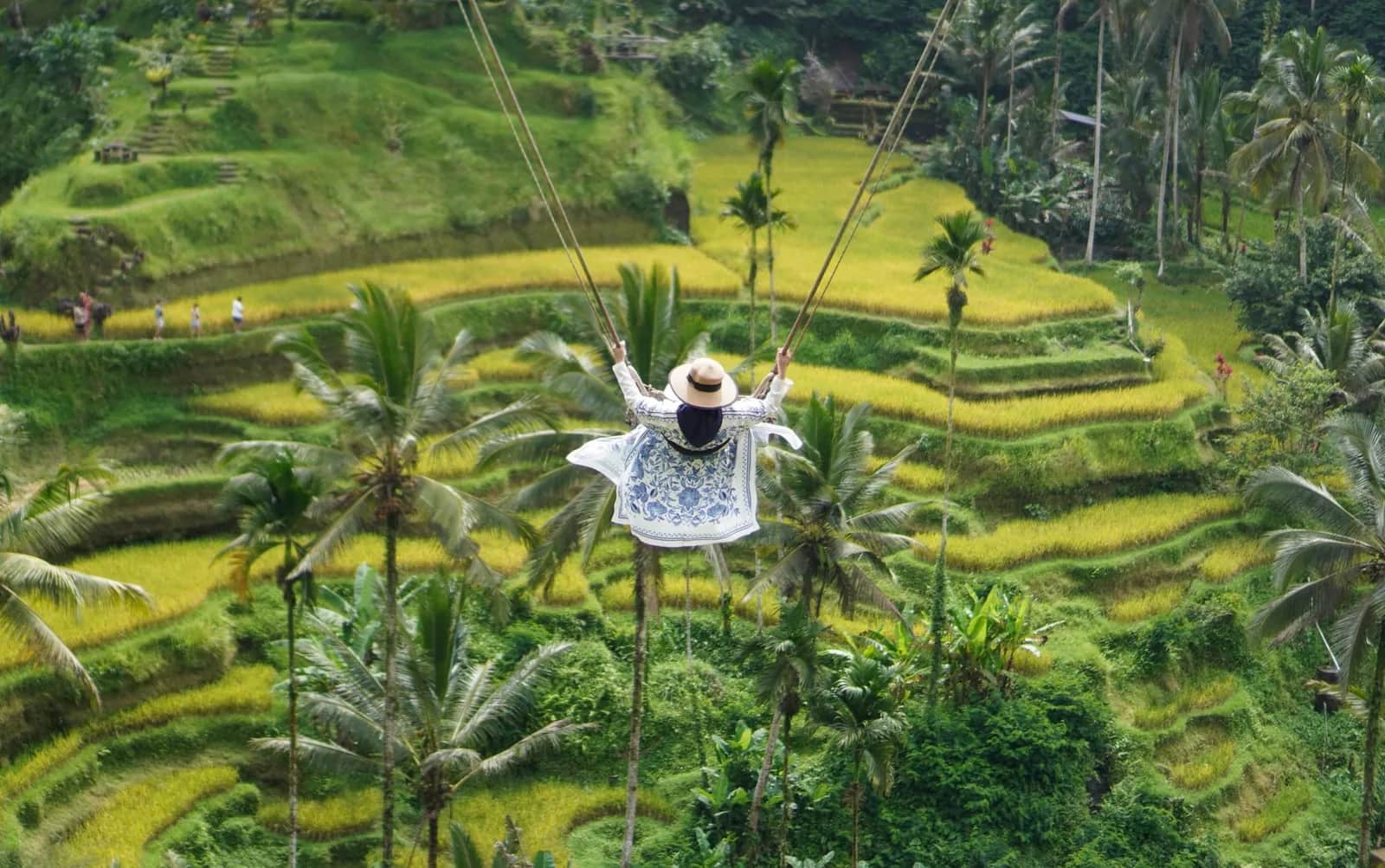 Femme en chapeau sur une balançoire géante lancée au-dessus des rizières en terrasses de Tegallalang près d'Ubud à Bali
