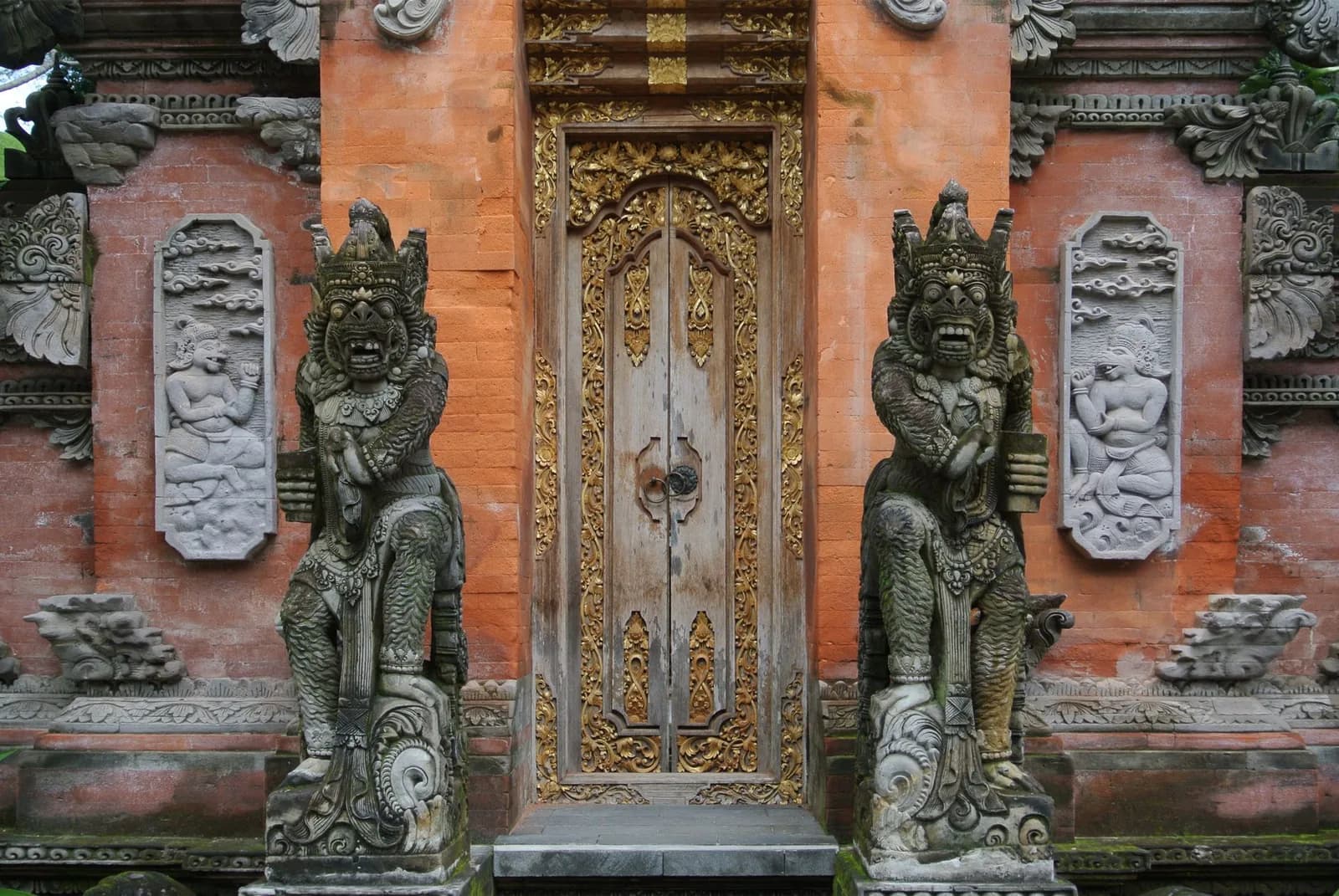 Porte sculptée et statues gardiennes d'un temple-palais à Ubud, Bali