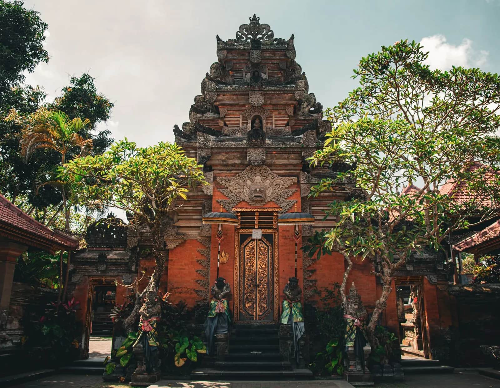 Porte sculptée et statues de pierre à l'entrée du palais royal d'Ubud, le Puri Saren Agung, à Bali