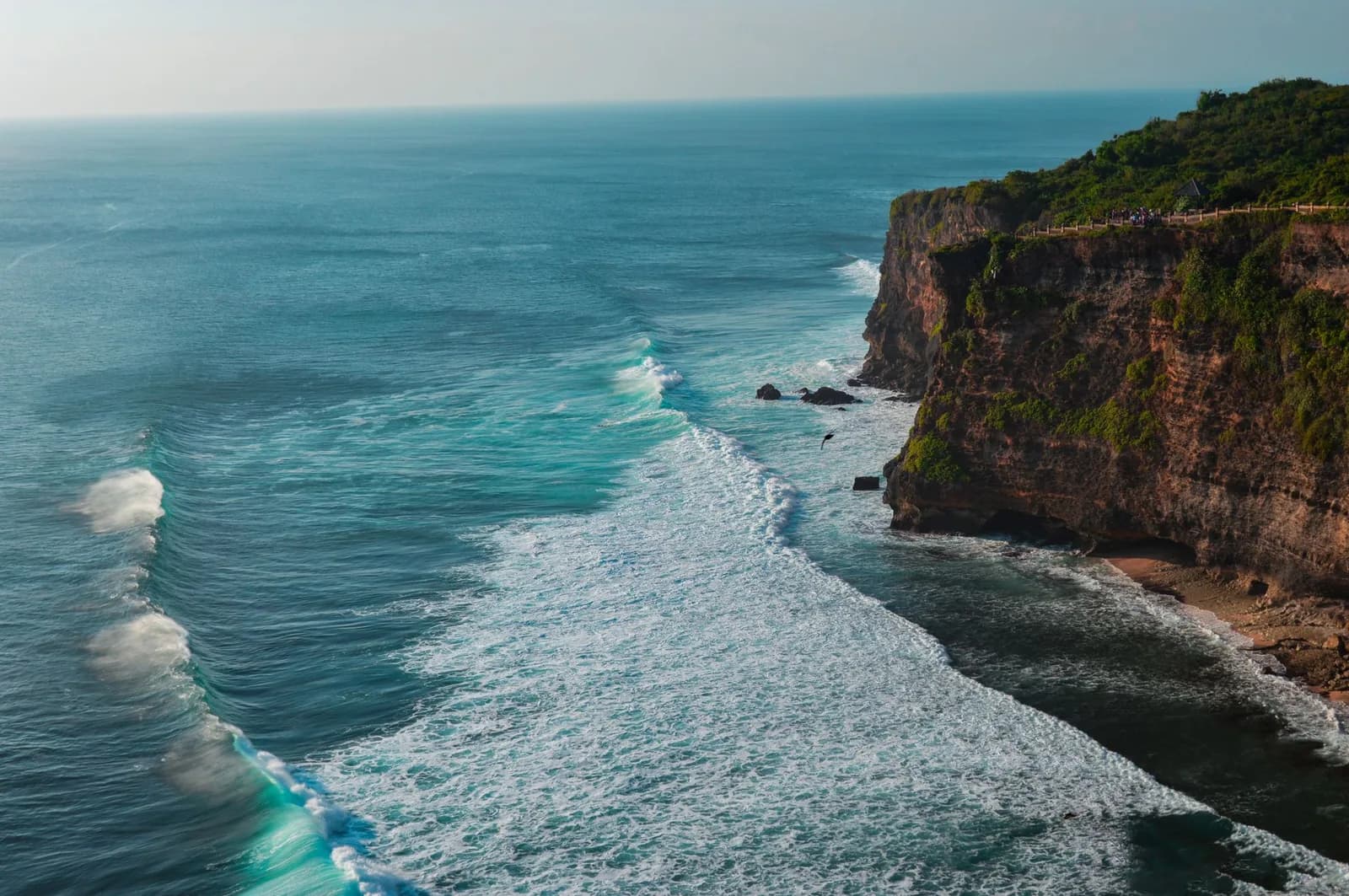 La houle qui déroule le long de la falaise d'Uluwatu, avec le belvédère du temple posé sur le promontoire, au sud de Bali