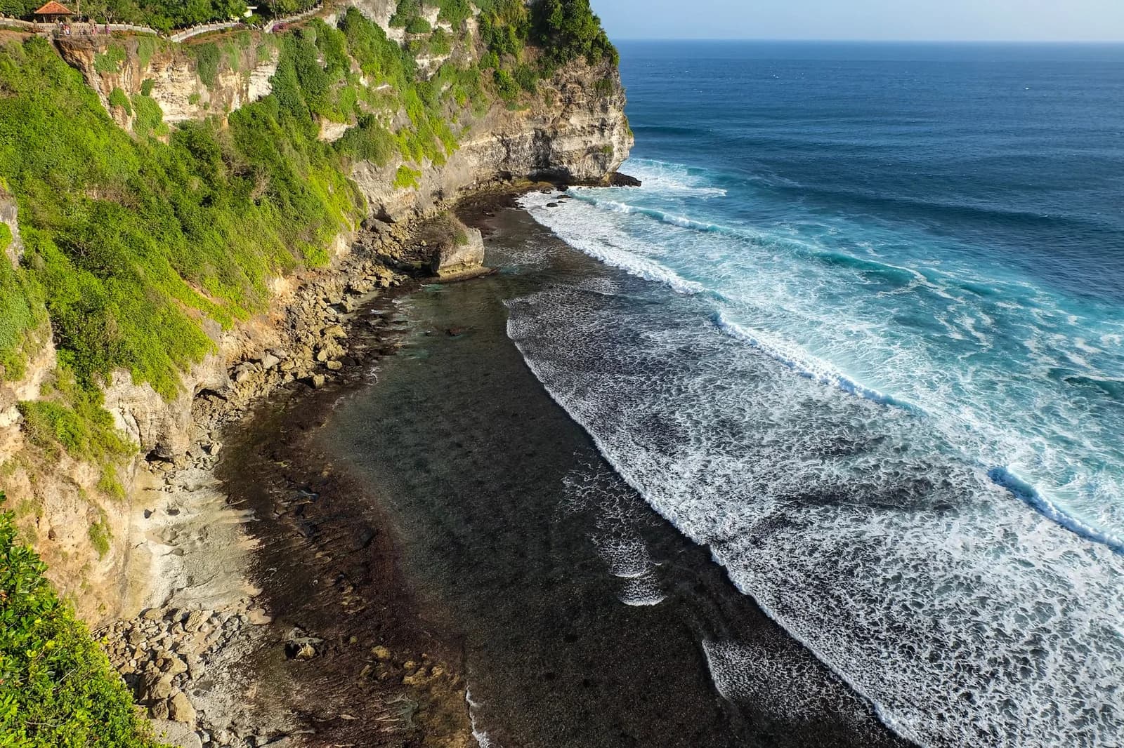 Houle déferlant sur le platier récifal au pied des falaises d'Uluwatu, Bali