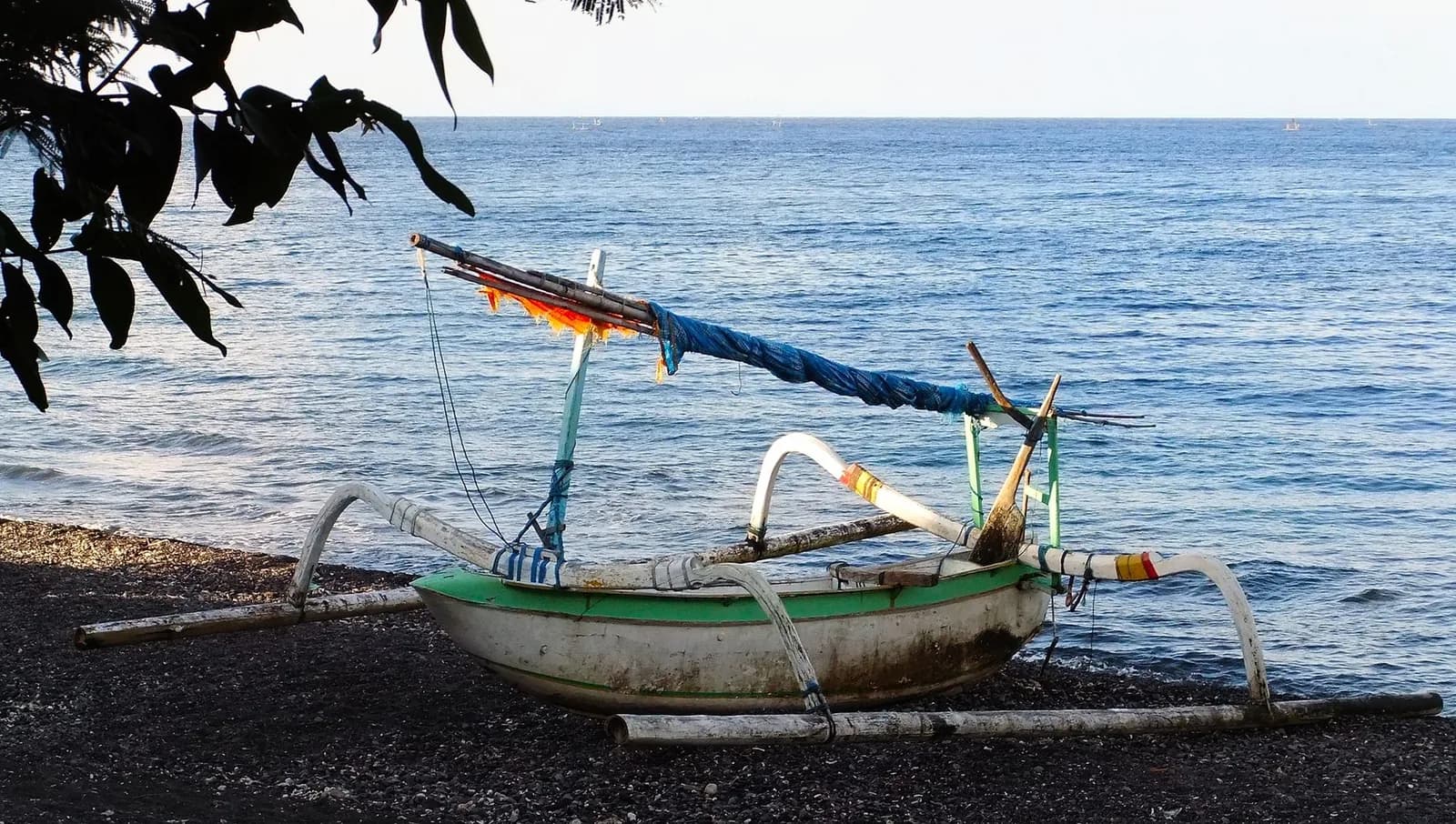 Pirogue de pêche jukung posée sur la plage de sable noir volcanique d'Amed, est de Bali