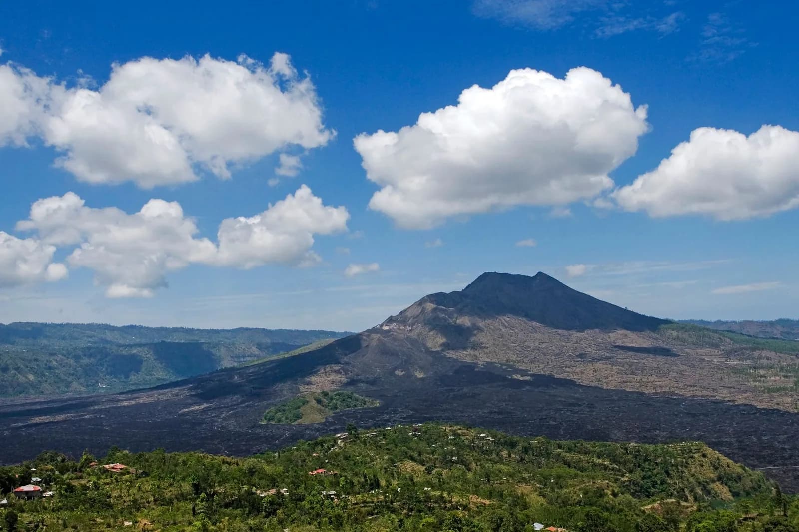 Le mont Batur et son champ de lave noire vus depuis la crête de Kintamani sous un ciel bleu, Bali