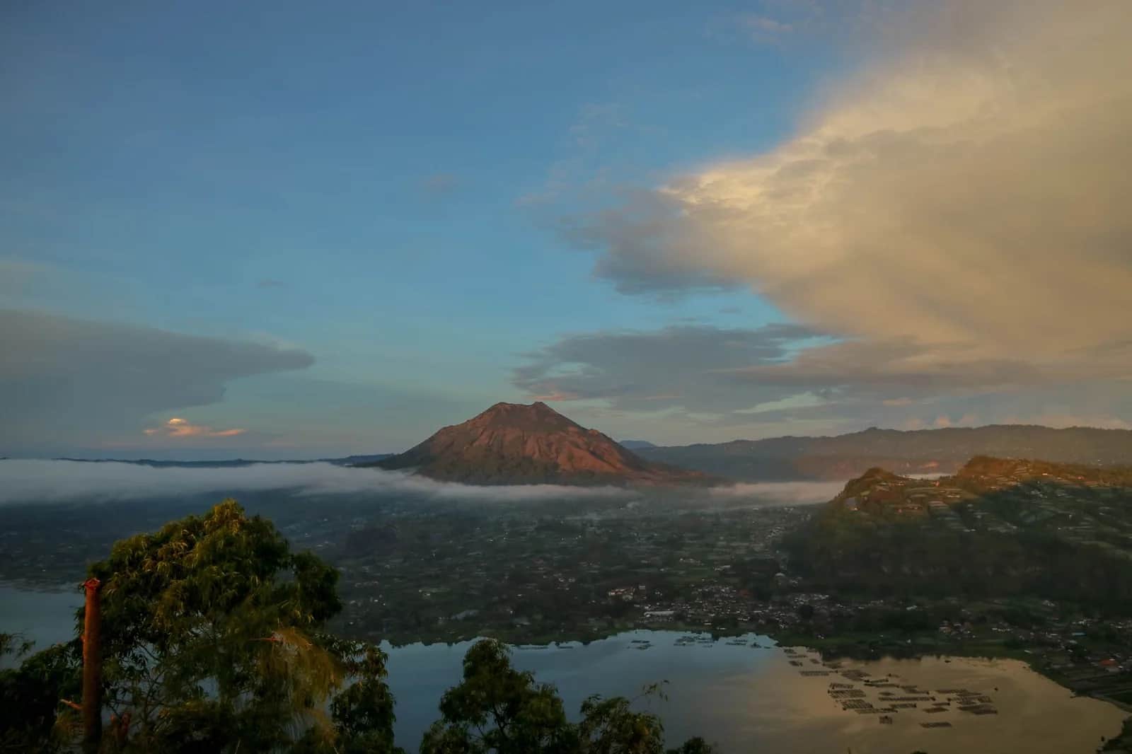 Le cône du mont Batur émergeant de la brume au-dessus du lac au lever du jour, Bali