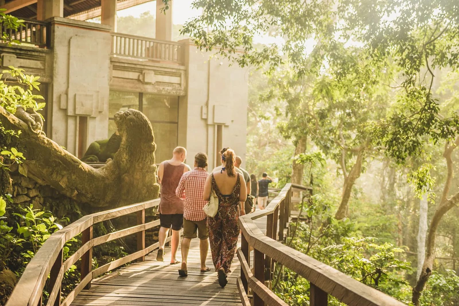 Petit groupe de voyageurs sur la passerelle en bois de la Monkey Forest d'Ubud, à Bali, près d'une statue de dragon